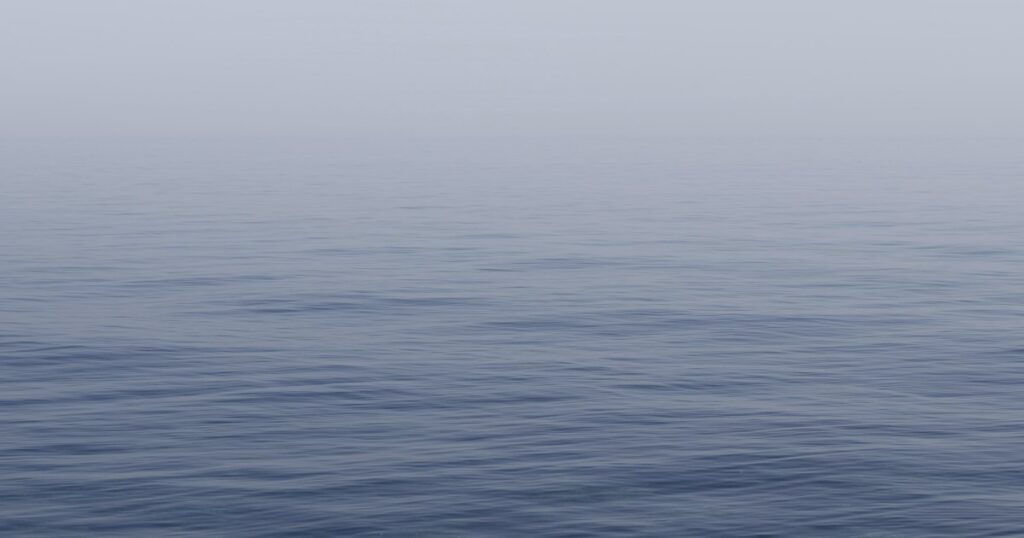 Спокойное серое море и мягкий свет над горизонтом